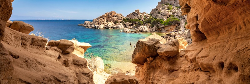 High-contrast coastal view framed by a rocky cave, showcasing vibrant colors boosted by rare earths lens technology.
