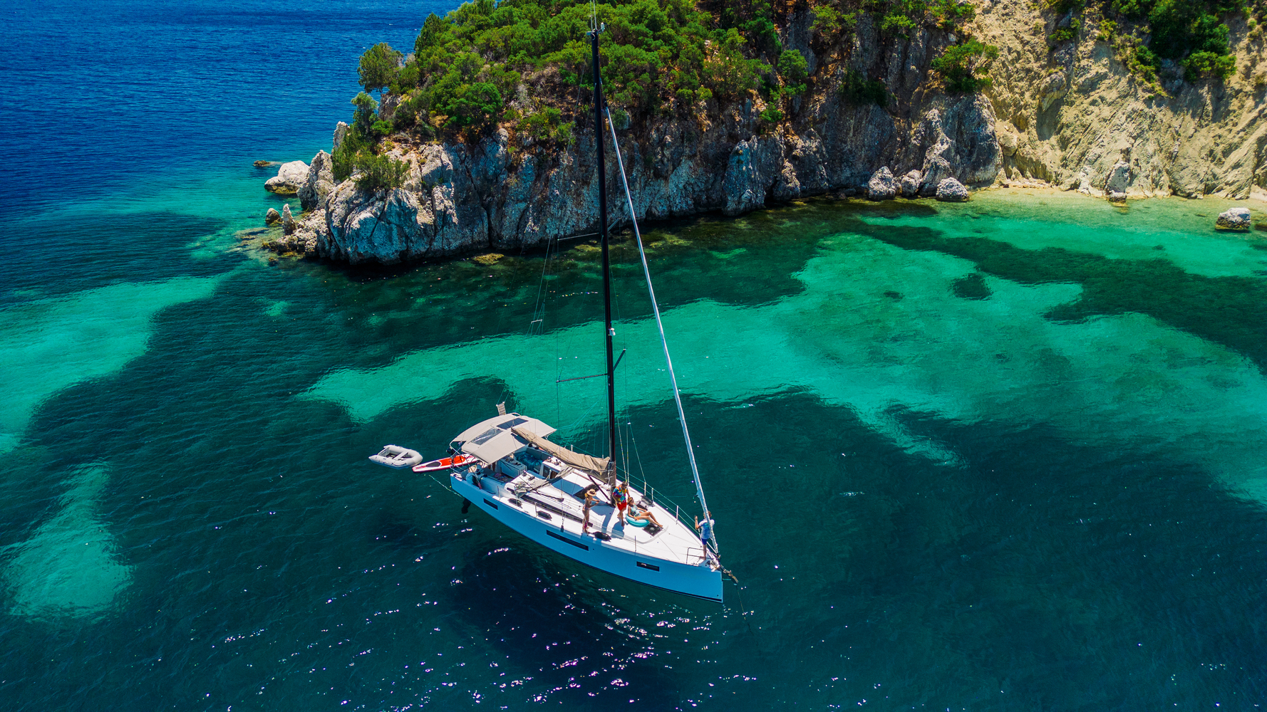Aerial view of a sailboat in crystal-clear turquoise water, demonstrating the reflection-free benefits of polarized lenses.