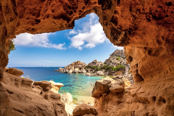 Vista costiera ad alto contrasto incorniciata da una grotta rocciosa, con colori vividi esaltati dalla tecnologia Terre Rare.