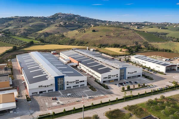 Aerial view of the Barberini Lenses manufacturing facility with extensive rooftop solar panels, surrounded by Italian hills.